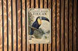 A vintage-style metal sign with a colorful illustration of a toucan perched on a branch, mounted on a wooden wall.