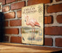 a vintage-style poster of a pink flamingo standing on a brick wall.