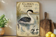 A framed illustration of a black and white duck swimming in a body of water, with text describing the bird and its habitat.
