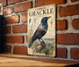 a vintage-style illustration of a Common Crackle bird perched on a tree stump, with a brick wall in the background.