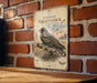 a vintage-style metal sign with a bird illustration, mounted on a brick wall.