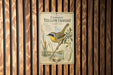 a vintage-style illustration of a yellow throatbird perched on a branch, with detailed botanical illustrations and text providing information about the bird.
