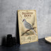 A vintage-style metal sign featuring an illustration of a diamond dove, with text describing the bird and its habitat.