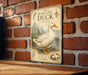 A vintage-style metal sign featuring an illustration of a domestic duck, mounted on a brick wall.