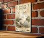 a vintage-style metal sign with a detailed illustration of a domestic goose, mounted on a brick wall.