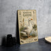 a vintage-style metal sign with a detailed illustration of a domestic goose, placed on a countertop next to some black camera lenses.