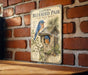 A vintage-style metal sign with illustrations of a bluebird and a birdhouse, mounted on a brick wall.