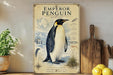 a poster of an Emperor Penguin on a shelf, with a potted plant to the left and a wooden cutting board to the right.