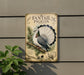 a vintage-style metal sign with a detailed illustration of a white and gray pigeon perched on a branch, surrounded by pine needles and other natural elements.