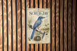 A vintage-style metal plaque with a blue bird illustration and text, mounted on a wooden wall.