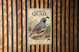 A metal sign with a picture of a quail standing on a wooden fence.