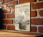 a metal sign with a detailed illustration of a gull, mounted on a brick wall.
