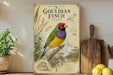 a poster of a colorful bird, specifically a Gouldian finch, perched on a branch surrounded by various plants and flowers. The poster is displayed on a wall, and there are some kitchen utensils, such as a cutting board and a knife, visible in the background.