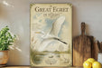 A vintage-style metal sign with a white egret illustration and text, placed on a wooden shelf next to a wooden cutting board and a potted plant.