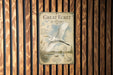 a poster with a large white bird in flight, displayed on a wooden wall.