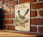 a vintage-style metal sign with a depiction of a roadrunner, mounted on a brick wall.