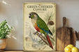 a poster of a colorful parrot, specifically a green-cheeked conure, perched on a branch. The poster is displayed on a shelf next to a wooden cutting board and a potted plant.