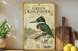 A vintage-style poster of a green kingfisher bird is displayed on a shelf, surrounded by kitchen utensils and a potted plant.