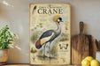 a vintage-style illustration of a grey crowned crane, a large wading bird, standing on a wooden surface. The illustration includes various details about the crane, such as its size, color, and habitat. The background of the illustration depicts a natural setting with grass, water, and other wildlife elements. The image also includes a list of the crane's characteristics and features, such as its long neck, large beak, and distinctive crest.
