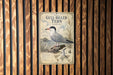 a vintage-style metal plaque with a detailed illustration of a gull-billed tern, mounted on a wooden wall.