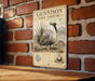 A metal sign with a detailed illustration of a Gunnison Sage-Grouse, a bird species, mounted on a brick wall.