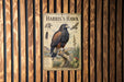 A vintage-style metal sign with illustrations and text about the Harris's Hawk, mounted on a wooden wall.