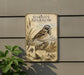 A vintage-style metal plaque with illustrations and text, mounted on a wall next to a plant.