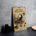 a vintage-style metal sign with illustrations of ducks and other wildlife, placed on a gray countertop next to some black camera lenses.