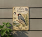 a vintage-style metal sign with illustrations and text, mounted on a wall next to a plant.