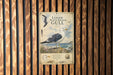 a metal sign with a black and white illustration of a gull, mounted on a wooden wall.