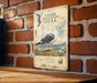 a vintage-style metal sign with an illustration of a seagull, mounted on a brick wall.