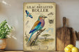 a poster of a colorful bird, specifically a lilac-breasted roller, perched on a branch. The poster is displayed on a wall, with a wooden cutting board and a potted plant visible in the foreground.