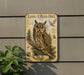 a large metal sign with an illustration of a long-eared owl perched on a branch, surrounded by various owl-related elements such as pine trees and pine cones.