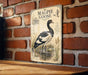 a vintage-style illustration of a magpie goose on a brick wall, with a wooden table below it.