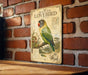 a vintage-style metal sign with a detailed illustration of a masked lovebird perched on a branch, mounted on a brick wall.