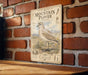 a vintage-style metal sign with a bird illustration, mounted on a brick wall.