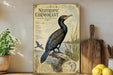 a poster of a cormorant bird, which is a type of wading bird, displayed on a shelf next to a wooden cutting board and some lemons.