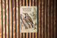 a vintage-style metal sign with a wood-paneled background, depicting a red-shapped bird perched on a tree branch.