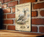 A vintage-style metal sign depicting a Pilgrim Goose, with illustrations and text providing information about the bird.