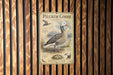A vintage-style metal sign with illustrations and text about a Pilgrim Goose, mounted on a wooden wall.