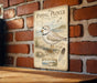 a vintage-style metal sign with an illustration of a piping plover bird, mounted on a brick wall.