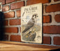 a metal sign with an illustration of a peregrine falcon, mounted on a brick wall.