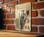 a vintage-style metal sign with illustrations and text, mounted on a brick wall.