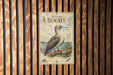 a metal sign with a bird illustration, mounted on a wooden wall.