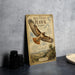 a vintage-style metal sign with an illustration of a red-tailed hawk soaring in the sky, placed on a gray countertop next to some black camera lenses.