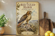 a poster of a red-tailed hawk with a prey, displayed on a shelf next to a wooden cutting board and some lemons.