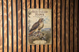 a vintage-style sign with a red-tailed hawk illustration, mounted on a wooden wall.