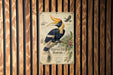 a vintage-style metal sign with an illustration of a hornbill bird, mounted on a wooden wall.