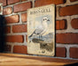 A vintage-style metal sign featuring a detailed illustration of a seagull perched on a rock, with text providing information about Ross's Gull.