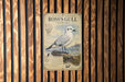 A vintage-style metal sign with a detailed illustration of a seagull perched on a rock, surrounded by grass and a birdhouse.
